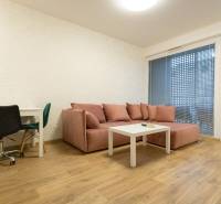 Zariadený 2i byt s lodžiou v rezidencii Pri Mýte - Obývacia izba v 2-izbovom byte s pohovkou, stolom a podlahou s dreveným dekorom.