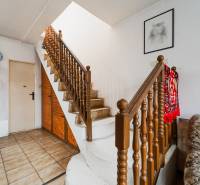 Pozemky s dvoma domami na prestavbu alebo novostavbu - Interiér rodinného domu so schodiskom, sýtočerveným kobercom a obrazom na stene.