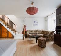 Pozemky s dvoma domami na prestavbu alebo novostavbu - Obývacia izba v rodinnom dome s dreveným schodiskom, pohovkou, skrinkou a podlahou s dreveným dekorom.