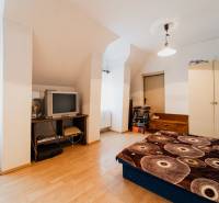 Pozemky s dvoma domami na prestavbu alebo novostavbu - Spálňa v rodinnom dome s podlahou s dreveným dekorom, starším televízorom a úložným priestorom.