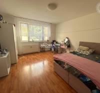 Predaj, trojizbový byt Levice, Rybníky V - Spálňa v 3-izbovom byte s podlahou s dreveným dekorom a veľkým oknom.