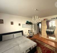 Predaj, trojizbový byt Levice, Rybníky V - Spálňa s lusterom a skriňou, podlaha s dreveným dekorom v 3-izbovom byte.