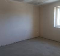 PREDAJ/ Kompletne zrekonštruovaný rodinný dom v Rožňave - Prázdna izba s betónovou podlahou a veľkým oknom v rodinnom dome.