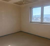 PREDAJ/ Kompletne zrekonštruovaný rodinný dom v Rožňave - Izba v rodinnom dome s omietnutými stenami a veľkým oknom.