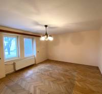 REZERVOVANÉ - Veľký 2-izbový byt s loggiou v centre Martina - Izba v 2-izbovom byte s podlahou s dreveným dekorom a centrálnym lustrom.