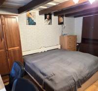 Na predaj 2 izbový rodinný dom, Dolné Orešany! - Spálňa v rodinnom dome s dreveným trámovým stropom, nábytkom a dekoratívnymi obrazmi.