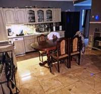 Rodinný dom na veľkorysom pozemku v Drahňove. - Kuchyňa v rodinnom dome s keramickou dlažbou, drevené skrinky a jedálenský stôl.