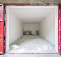 Pozrite si 17m², ZREKONŠTRUOVANÚ garáž, pri nemocnici Kramáre - Otvorená garáž so skladovanými predmetmi na ulici Opavská a Garáže, červené dvere.