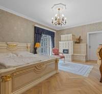 Exkluzívna honosná kúria | 3 ha pozemok | Dunakiliti - HU - Luxusná spálňa so zlatými detailmi, podlahou s dreveným dekorom a kachľovou pecou.