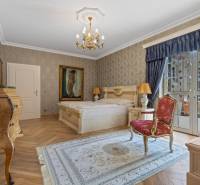 Exkluzívna honosná kúria | 3 ha pozemok | Dunakiliti - HU - Luxusná spálňa so zlatými prvkami, lustrom a podlahou s dreveným dekorom.