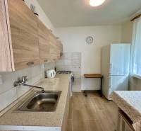 Prenájom 3 izbového bezbariérového bytu, Vetvová ulica, Bratislava - Kuchyňa v 3-izbovom byte s podlahou s dreveným dekorom a bielymi stenami.