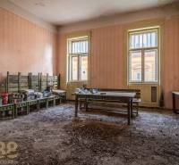Exkluzívne: Predaj budovy v centre mesta Poprad - Ošúchaná izba s lavicami a neporiadkom v starej budove.