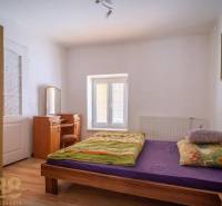 Exkluzívne: Predaj budovy v centre mesta Poprad - Spálňa s posteľou, zrkadlom a podlahou s dreveným dekorom.