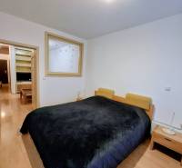 SLNEČNÝ KOMPLETNE ZARIADENÝ 2 IZB. BYT PRI ŠTRKOVECKOM JAZERE.  - Spálňa so širokou posteľou, nočnými stolíkmi a podlahou s dreveným dekorom v 2-izbovom byte.