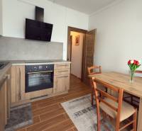 3-izbový zariadený byt, 78 m2, zasklenná loggia, Považská ul., Nitra - Kuchyňa v 3-izbovom byte s dreveným dekorom, jedálenským stolom a kuchynskou linkou.