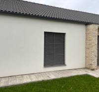 Na predaj dizajnový 4-izbový rodinný dom v Tomášove - Exteriér rodinného domu na Fialkovej v Tomášove s tehlovým obkladom a trávnikom.