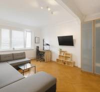 Svetlý, jedinečný 2i byt 62m2, po rekonštrukcií, s pivnicou   - Obývačka v 3-izbovom byte s rohovou sedačkou, pracovným stolom a podlahou s dreveným dekorom.