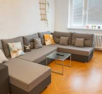 Svetlý, jedinečný 2i byt 62m2, po rekonštrukcií, s pivnicou   - Obývačka s pohodlnou sedačkou a podlahou s dreveným dekorom v 3-izbovom byte.