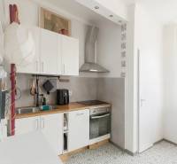 Svetlý, jedinečný 2i byt 62m2, po rekonštrukcií, s pivnicou   - Kuchyňa v 3-izbovom byte s dlažbou, bielymi skrinkami a dreveným dekorom pultu.