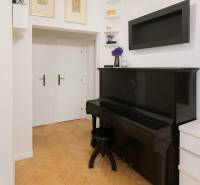 Svetlý, jedinečný 2i byt 62m2, po rekonštrukcií, s pivnicou   - Interiér 3-izbového bytu so starožitným čiernym klavírom a podlahou s dreveným dekorom.