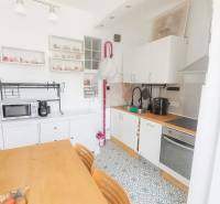 Svetlý, jedinečný 2i byt 62m2, po rekonštrukcií, s pivnicou   - Kuchyňa v 3-izbovom byte s jedálenským stolom, vzorovanou podlahou a bielymi skrinkami.