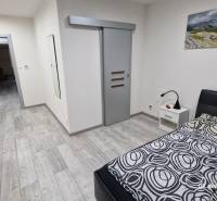 Nový rodinný dom, 7 minút od centra Košíc v tichej uličke pod lesom - Spálňa v rodinnom dome s podlahou s dreveným dekorom a posuvnými dverami.