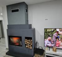 Nový rodinný dom, 7 minút od centra Košíc v tichej uličke pod lesom - Interiér rodinného domu s krbom a televíziou na podlahe s dreveným dekorom.