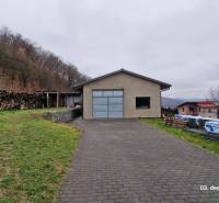 Nový rodinný dom, 7 minút od centra Košíc v tichej uličke pod lesom - Rodinný dom na Kopaninovej ulici v Sokolí obklopený prírodou, hromada dreva a príjazdová cesta.