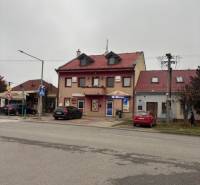 Podkrovná kancelária – ŠAFÁRIKOVA UL., SENEC - Budova s červenou strechou a obchodmi na Šafárikovej ulici, Senec, vhodná pre kancelárie.