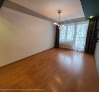 Na predaj priestranný 4-izbový byt 87 m2, Považská Bystrica - Obývačka 4-izbového bytu s podlahou s dreveným dekorom a veľkým oknom.