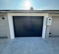 PREDAJ zrekonštruovaná garáž na ulici Slnečná - KOMÁRNO - Garáže na Slnečnej ulici v Komárne s tmavými bránami a betónovou plochou.