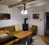 Na predaj vidiecky rodinný dom v obci Dolný Pial - Obývacia izba rodinného domu s kachľami, starožitným nábytkom a dekoráciami.