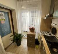 V exkluzívnom zastúpení majiteľa ponúkame na predaj rodinný dom - Kuchyňa v rodinnom dome s plynovým sporákom, rastlinou a oknom s bielou záclonou.