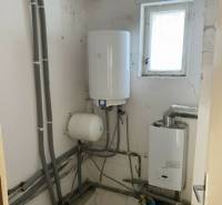 V exkluzívnom zastúpení majiteľa ponúkame na predaj rodinný dom - Interiér rodinného domu s kotlom a potrubím, biela stena s oknom.