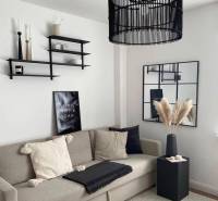 Exkl.4 iz novostavba RD - tepelné čerpadlo - Moravany nad Váhom - Obývačka v rodinnom dome s pohodlnou sedačkou, dekoratívnymi poličkami a moderným lustrom.