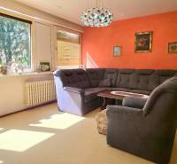 SLOVREAL - Predaj rodinného domu - Handlová - Obývačka v rodinnom dome s oranžovou stenou, gaučom a veľkými oknami.