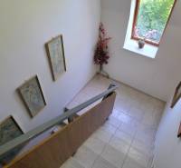 SLOVREAL - Predaj rodinného domu - Handlová - Schody v rodinnom dome s umením na stenách a výhľadom cez okno.