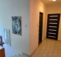 SLOVREAL - Predaj rodinného domu - Handlová - Chodba v rodinnom dome s umením na stenách a tmavými dverami.