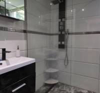 SLOVREAL - Predaj rodinného domu - Handlová - Kúpeľňa v rodinnom dome s bielymi obkladačkami a sprchovým kútom.