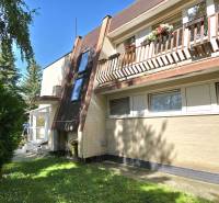 SLOVREAL - Predaj rodinného domu - Handlová - Exteriér rodinného domu v Handlovej s drevenou pergolou, trávnikom a balkónom s kvetmi.