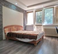 SLOVREAL - Predaj rodinného domu - Handlová - Spálňa v rodinnom dome s kamennou stenou a podlahou s dreveným dekorom.