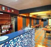 SLOVREAL - Predaj rodinného domu - Handlová - Interiér pohostinstva s barovým pultom a stolmi v rodinnom dome.