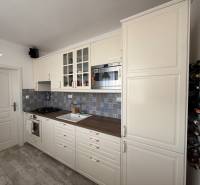 KRÁSNY, ÚTULNÝ A ŠTÝLOVÝ 3 IZBOVÝ BYT | DUBRAVKA - Kuchyňa v 3-izbovom byte s bielymi skrinkami a podlahou s dreveným dekorom.