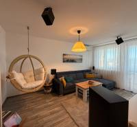 KRÁSNY, ÚTULNÝ A ŠTÝLOVÝ 3 IZBOVÝ BYT | DUBRAVKA - Obývačka s hojdačkou, rohovou sedačkou a podlahou s dreveným dekorom v 3-izbovom byte.