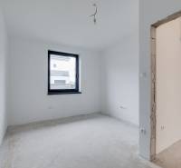 Novostavba samostatne stojaceho RD v štandarde, nízka spotreba - Izba v rodinnom dome s bielymi stenami a oknom, nedokončená podlaha.