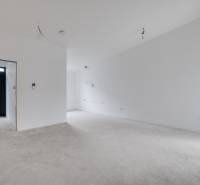 Novostavba samostatne stojaceho RD v štandarde, nízka spotreba - Priestranná miestnosť v rodinnom dome s bielymi stenami a betónovou podlahou.
