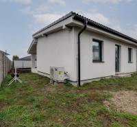 Novostavba samostatne stojaceho RD v štandarde, nízka spotreba - Rodinný dom na ulici Pri parku v Slovenskom Grobe s bielou fasádou a malým dvorom.