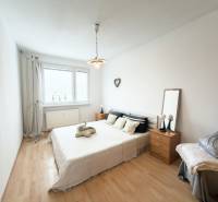 Na predaj 2,5- izbový byt Žilina-Solinky - Svetlá spálňa s posteľou a podlahou s dreveným dekorom v 2-izbovom byte.