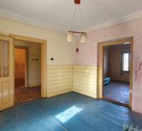 Rodinný dom v obci Čebovce v okrese Veľký Krtíš. - Izba s modrou podlahou s dreveným dekorom, starými dverami a prasklinami v stene.