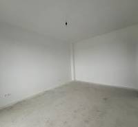 PREDAJ - 2-izbový byt v nádhernej lokalite Dvorníky - Prázdna miestnosť v 2-izbovom byte so sivou podlahou a bielymi stenami.